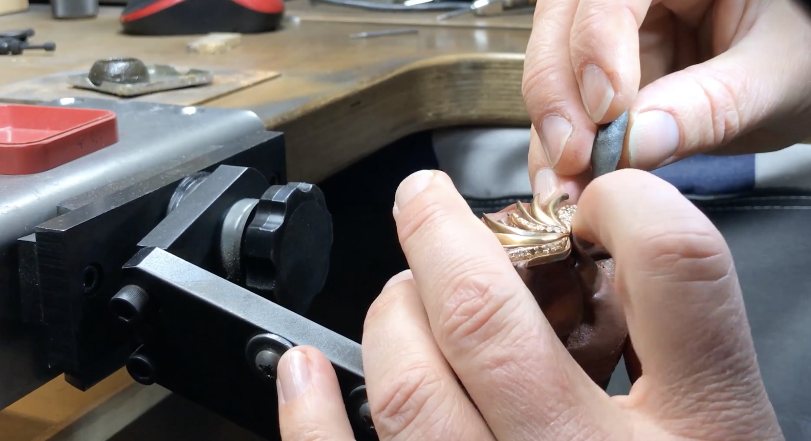 Hände beim Fassen eines Goldstücks mit Diamanten – Handwerkskunst im Detail