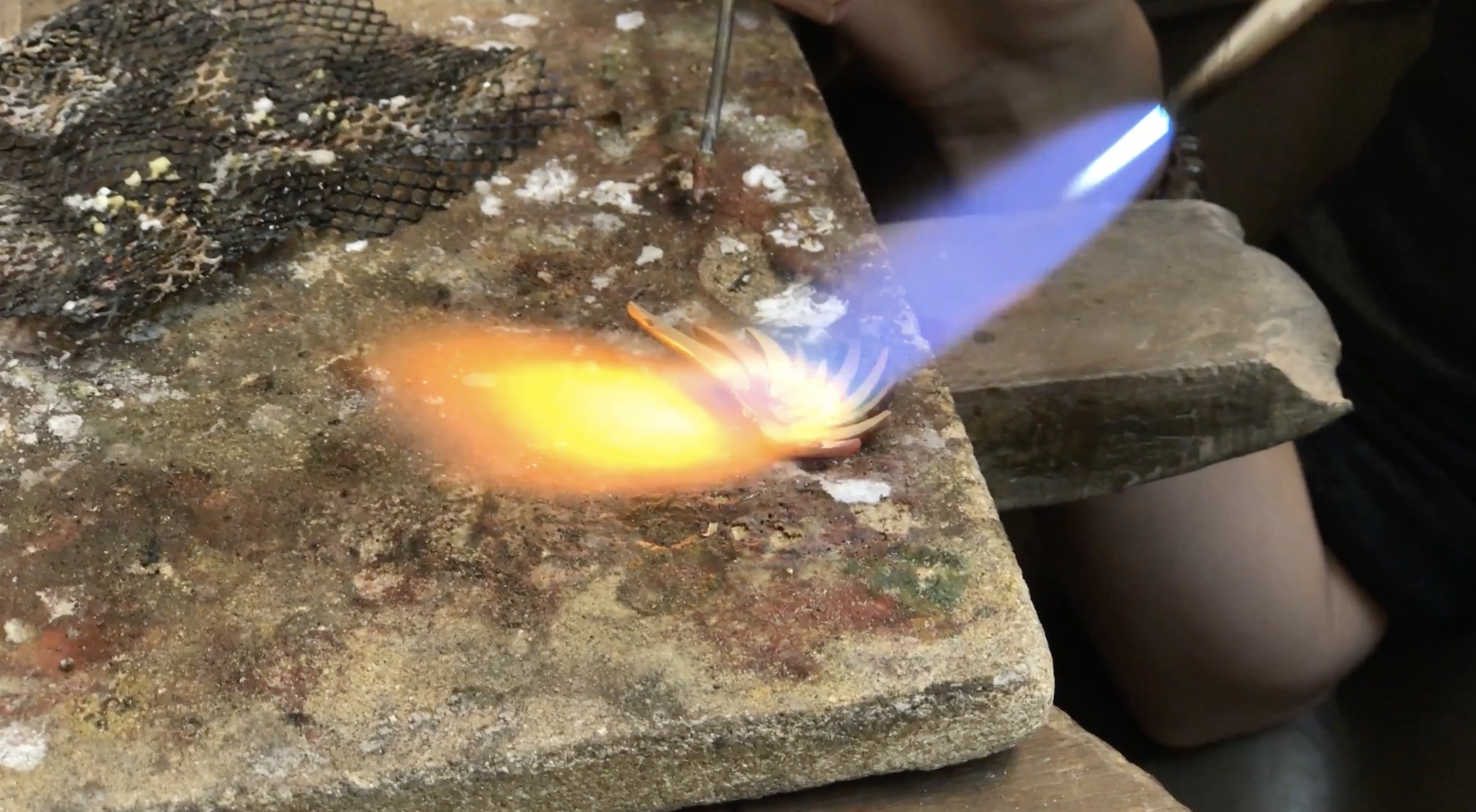 Lötflamme auf einem Goldstück in der Werkstatt – die Entstehung eines MXHM-Schmuckstücks