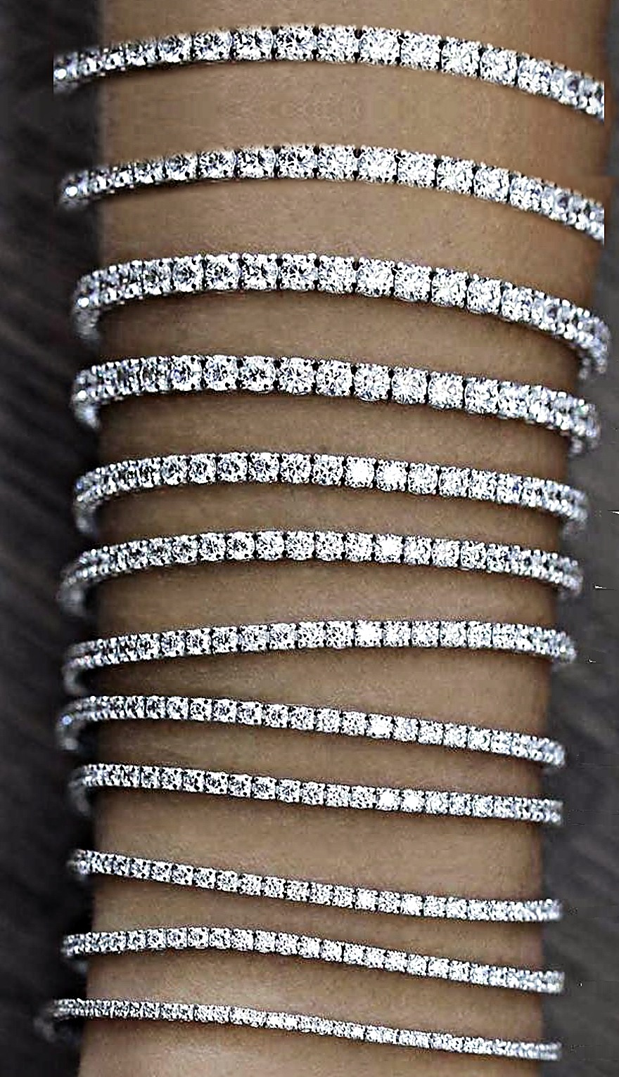 Zwölf weiße Tennisarmbänder von 1 bis 12 Karat übereinander am selben Handgelenk, Größenvergleich